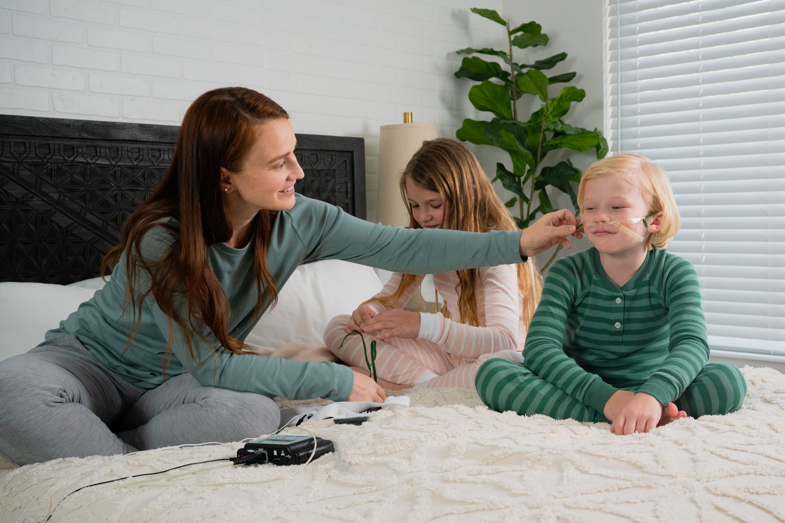 A parent helps her child apply the airflow sensor and nasal cannula